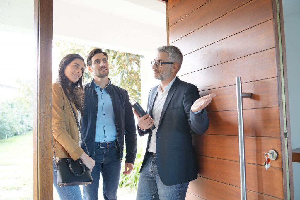 Couple With Real Estate Agent Visiting Modern House